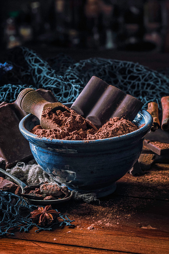 Close up of cocoa powder with chocolate bar into a blue bowl in old fashioned style