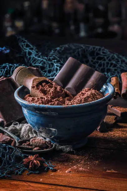 Photo of Close up of cocoa powder with chocolate bar into a blue bowl in old fashioned style