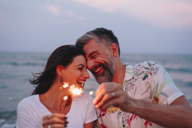 pareja celebrando con luces de bengala en la playa - esposa cónyugue fotos fotografías e imágenes de stock