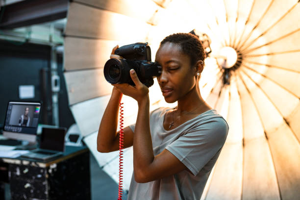 young photographer standing in front of a reflective umbrella - professional photographer imagens e fotografias de stock