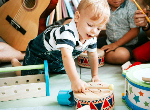 little kid playing with a wooden drum set - music lesson imagens e fotografias de stock