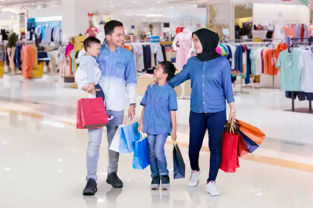 Picture of happy family carrying shopping bags while walking together in the mall