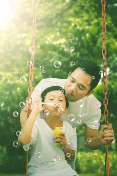 istock Child blowing soap bubbles with his father 1124340726