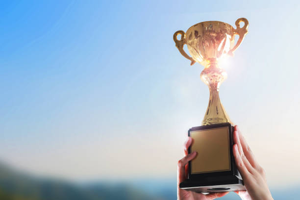 istock Business hands holding trophy cup on sky background. 1124340950