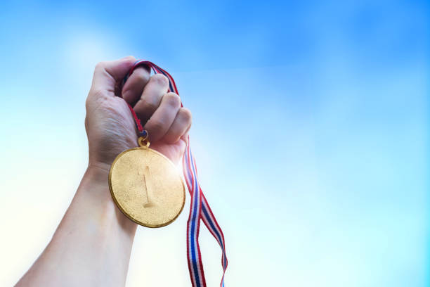 istock Athletic man hand holding golden coin medal. 1124341011