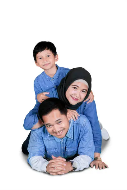 Portrait of happy family lying together on the floor while having fun in the studio, isolated on white background