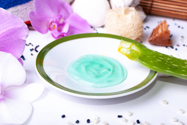 Close up of a set up of wellness items, a candle, stones, a beauty sponge, a sea star, towel, flowers, a natural sponge, aloe vera leave, aloe vera gel, wood, a bamboo mat, decorative stones, aloe vera leaf and aloe vera gel una puesta en marcha de os de bienestar, una vela, piedras, una esponja de belleza, una estrella de mar, toalla, flores, una esponja natural, deja de aloe vera, gel de aloe vera, madera, una estera de bambú, piedras decorativas, hoja de aloe vera y