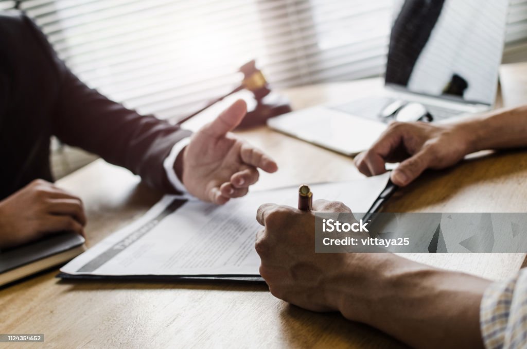client customer signing contract and discussing business with legal consultants, notary or justice lawyer with laptop computer and wooden judge gavel on desk in courtroom office, legal service concept Legislator Stock Photo