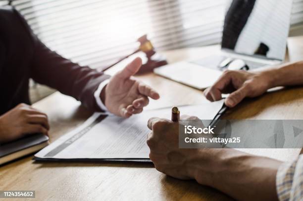 Client Customer Signing Contract And Discussing Business With Legal Consultants Notary Or Justice Lawyer With Laptop Computer And Wooden Judge Gavel On Desk In Courtroom Office Legal Service Concept Stock Photo - Download Image Now