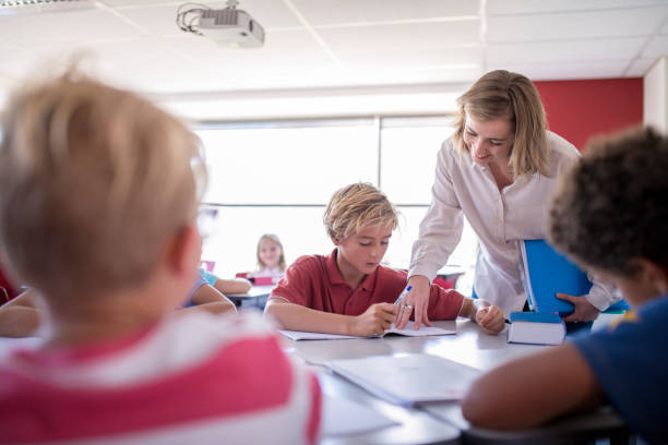 istock Young teacher explaining schoolboy sitting at desk 1124355482
