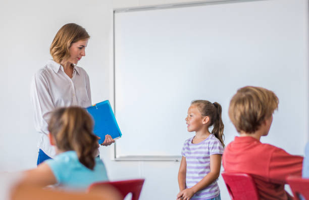 istock Young teacher talking with girl in classroom 1124355601
