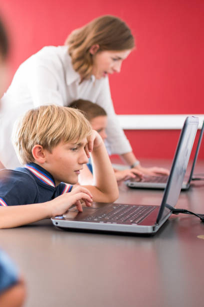 chłopiec za pomocą laptopa przy biurku w laboratorium komputerowym - computer lab child internet development zdjęcia i obrazy z banku zdjęć