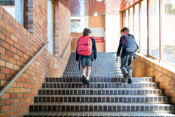 School children with backpacks walking upstairs Rear view of school children walking upstairs. Full length of girl and boy carrying backpacks. They are in elementary school. school boy in uniform stock pictures, royalty-free photos & images