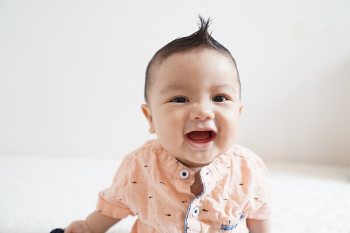 A series of photos of an Asian baby boy with multiple facial expressions including smiling, frowning, curious and big grins.