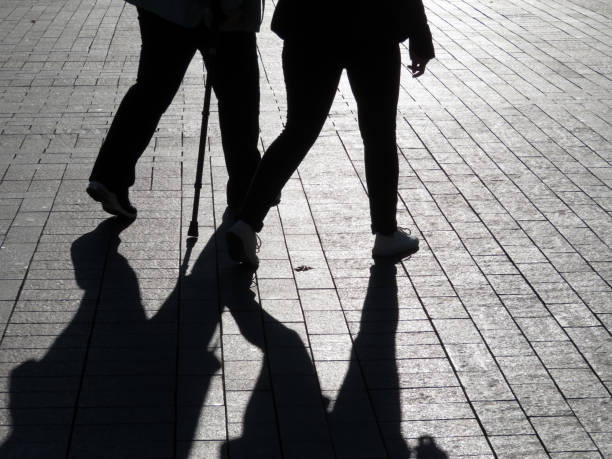 silhouetten und schatten von zwei menschen auf der straße - sidewalk walking human foot city stock-fotos und bilder