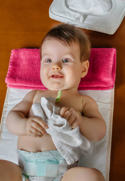 Baby lying playing with a small towel Adorable baby lying playing with a small white towel after the change of diaper blow up doll stock pictures, royalty-free photos & images