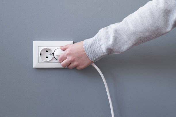 手挿入電気コンセントに差し込みます - electric plug outlet pulling electricity ストックフォトと画像