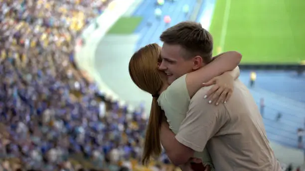 Young woman and guy hugging during football match favorite football team victory