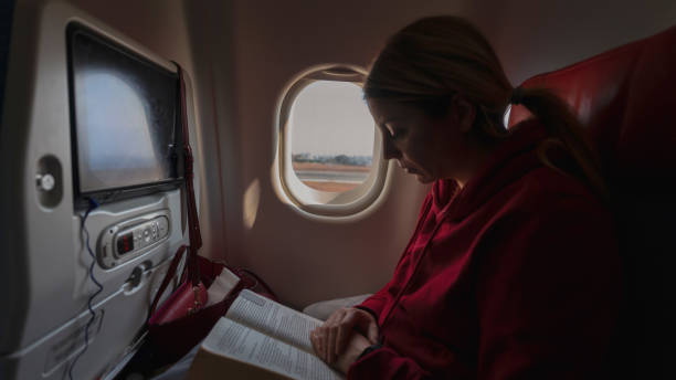 istock Blonde woman reading book on airplane 1124380918