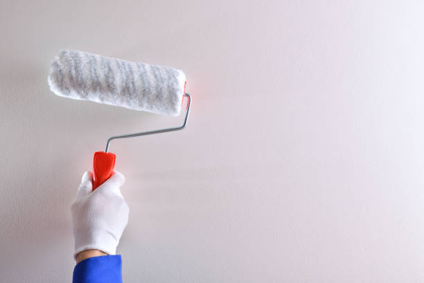 istock Hand of professional painter with roller on white wall 1124381789