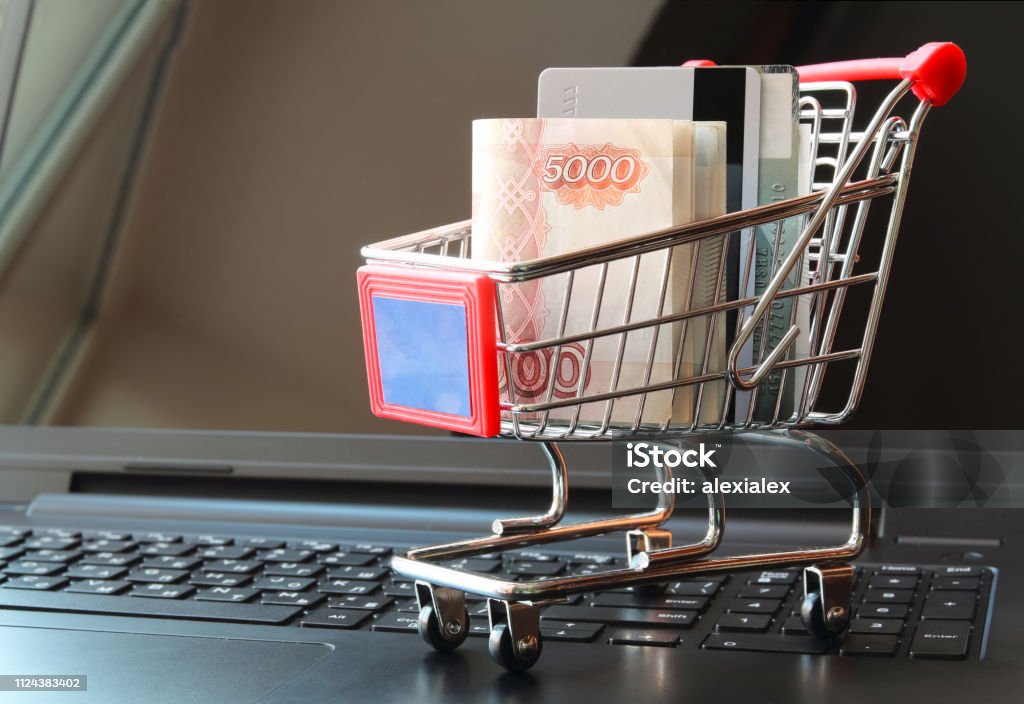 Shopping trolley with money russian rubles and credit cards on opened laptop. Shopping trolley with money russian rubles and credit cards on opened laptop. Shopping online concept. Russian Rubles Stock Photo