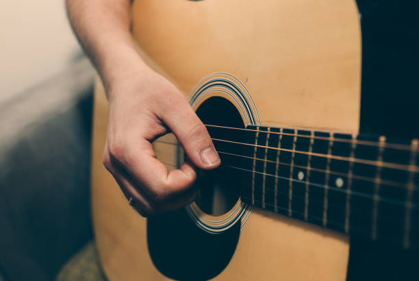 istock Man at home is playing the guitar. Guys hands are taking the chord on strings. Music making lifestyle concept. Free time hobby for everyone. Retro guitar photo. 1124387544