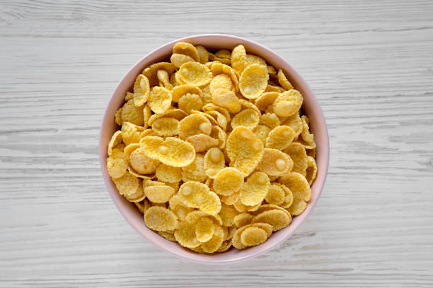 istock Corn flakes in a pink bowl for breakfast on a white wooden table, top view. Flat lay, overhead, from above. Close-up. 1124388722