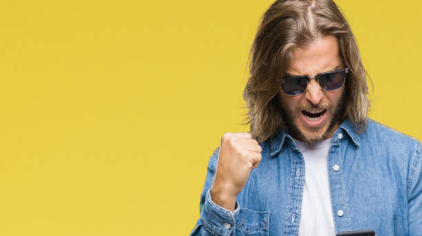 istock Young handsome man with long hair over isolated background sending message using smartphone annoyed and frustrated shouting with anger, crazy and yelling with raised hand, anger concept 1124391208