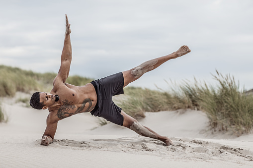 Beautiful brunette man during outdoor workout on the beach