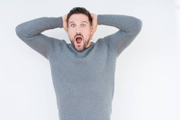 istock Young handsome man wearing casual sweater over isolated background Crazy and scared with hands on head, afraid and surprised of shock with open mouth 1124393997