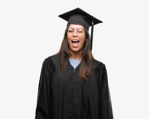 istock Young hispanic woman wearing graduated cap and uniform winking looking at the camera with sexy expression, cheerful and happy face. 1124400722