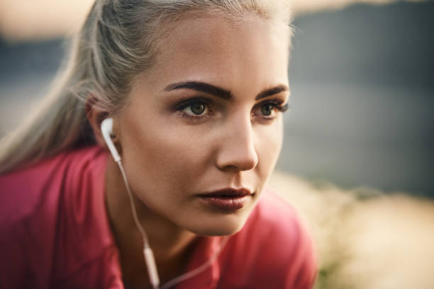 primo piano di runner donna che indossa auricolari - jogging autumn young women women foto e immagini stock