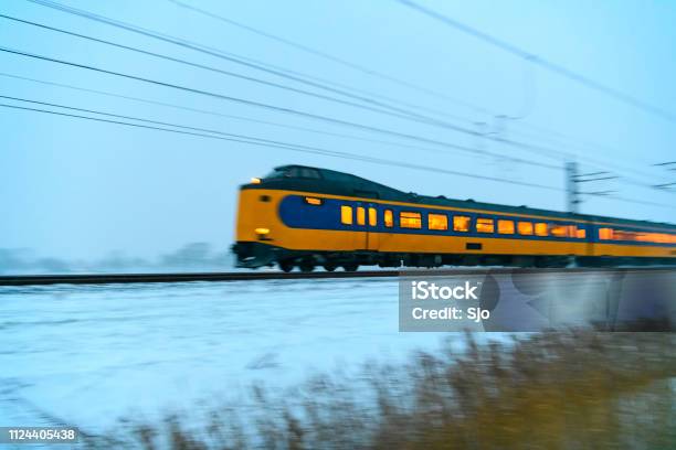 Intercity Train Of The Nederlandse Spoorwegen Driving Through The Snow During A Cold Winter Evening Stock Photo - Download Image Now