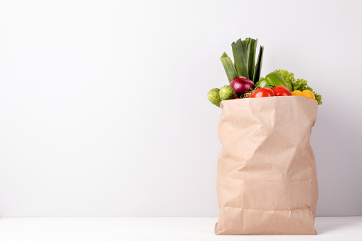 Bolso de compras de supermercado con alimentos sobre fondo gris photo