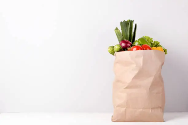 Photo of Grocery shopping bag with food on gray background