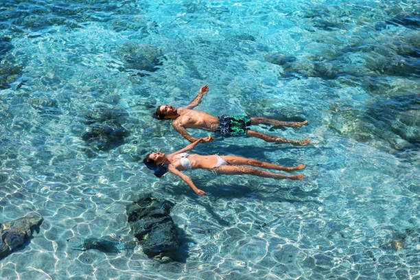 happy couple swimming in the transparent turquoise sea - summer swimming beach vacations imagens e fotografias de stock