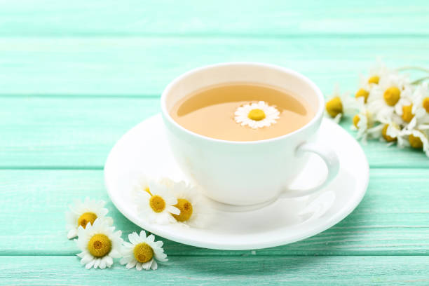 istock Cup of tea with chamomile flowers on mint wooden table 1124408929