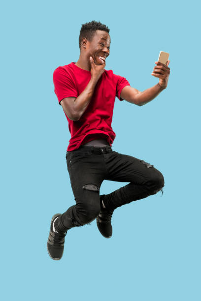 istock always on mobile. Full length of handsome young man taking phone while jumping 1124411581