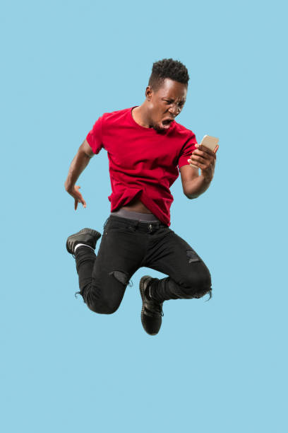 istock always on mobile. Full length of handsome young man taking phone while jumping 1124411584