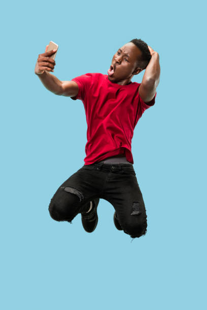 istock always on mobile. Full length of handsome young man taking phone while jumping 1124411587