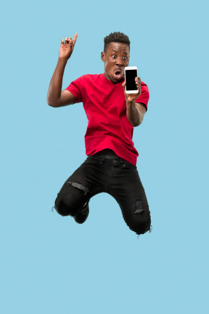 istock always on mobile. Full length of handsome young man taking phone while jumping 1124411591