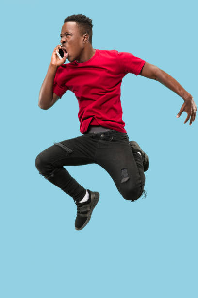 istock always on mobile. Full length of handsome young man taking phone while jumping 1124411593