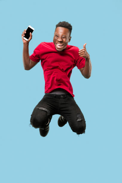 istock always on mobile. Full length of handsome young man taking phone while jumping 1124411596