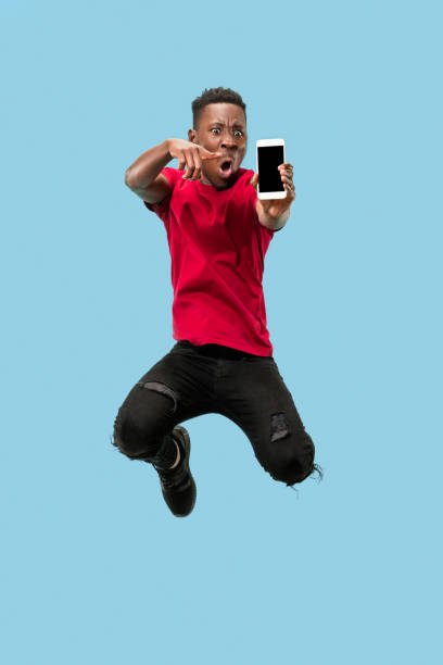 istock always on mobile. Full length of handsome young man taking phone while jumping 1124411597