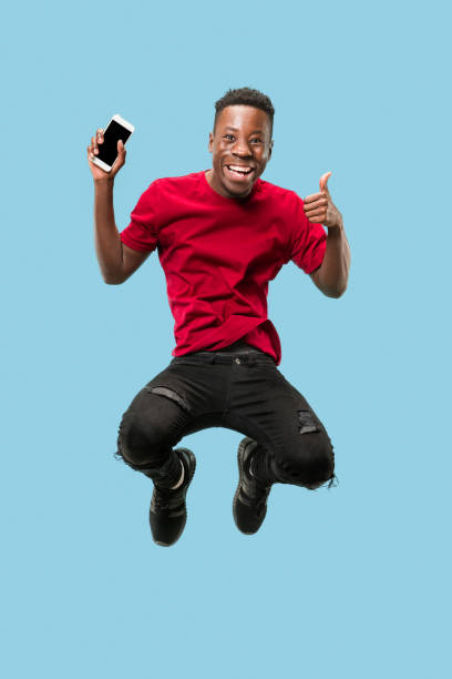 istock always on mobile. Full length of handsome young man taking phone while jumping 1124411607