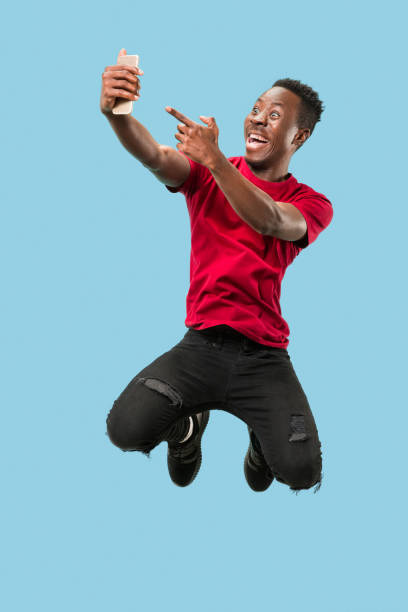 istock always on mobile. Full length of handsome young man taking phone while jumping 1124411615