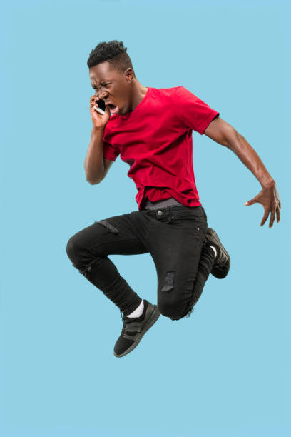 istock always on mobile. Full length of handsome young man taking phone while jumping 1124411618