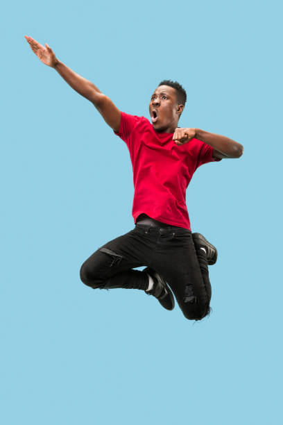 istock Freedom in moving and forward motion. The happy surprised young afro man jumping 1124411619
