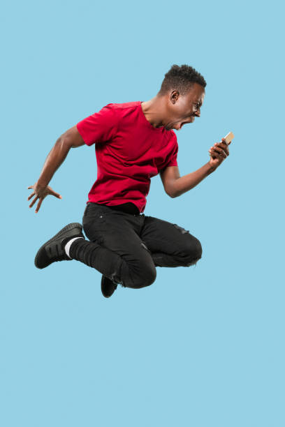 istock always on mobile. Full length of handsome young man taking phone while jumping 1124411625