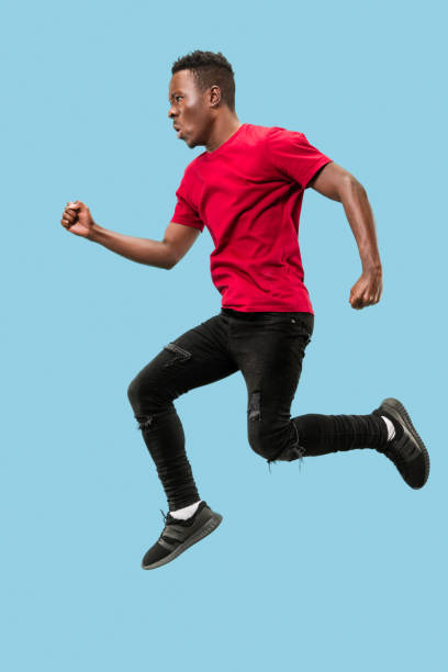 istock Freedom in moving and forward motion. The happy surprised young afro man jumping 1124411634